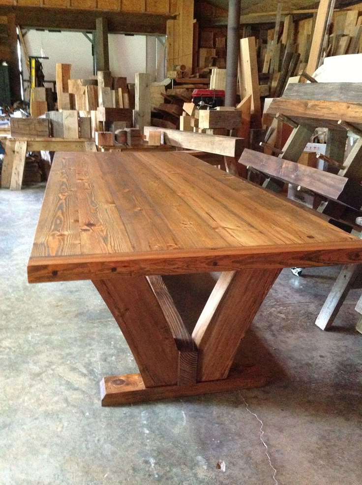 a wooden table sitting in a room filled with lots of wood planks on the floor