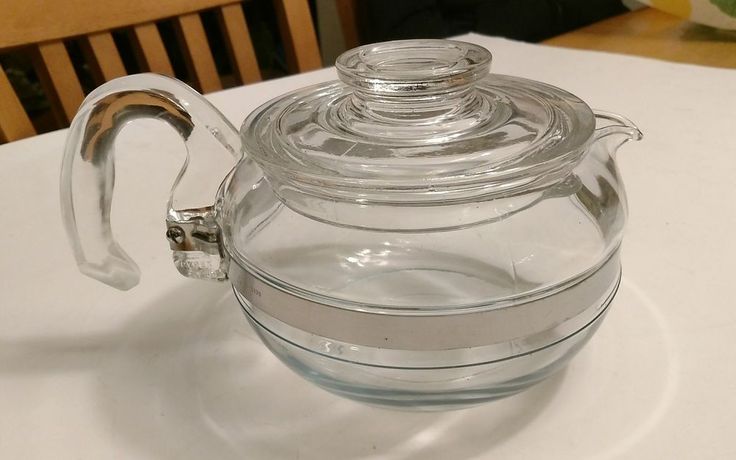 a glass tea pot with a lid on a table