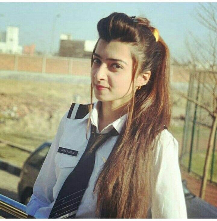 a girl with long hair wearing a tie and dress shirt is standing in front of a car