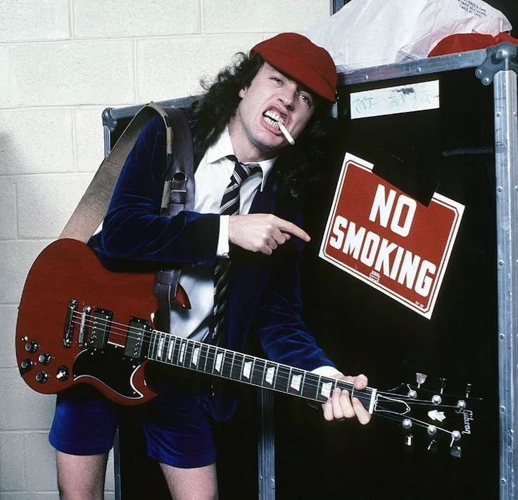 a man with long hair holding a red guitar