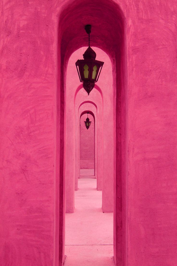 a pink hallway with a light on the wall