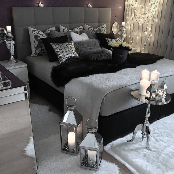 a large bed sitting in a bedroom next to two tables with candles on top of it