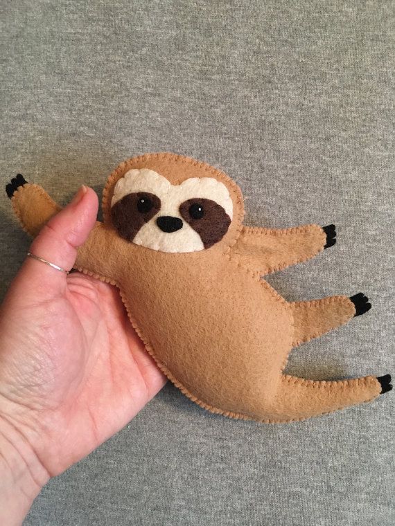 a hand holding a small stuffed sloth