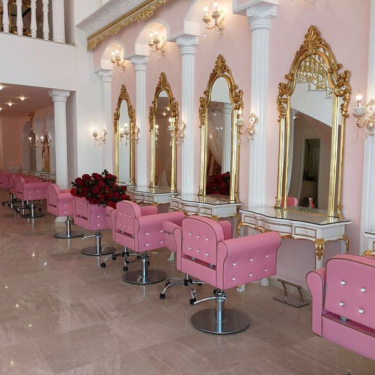 the salon is decorated in pink and gold with mirrors on the wall, chairs are lined up against the wall