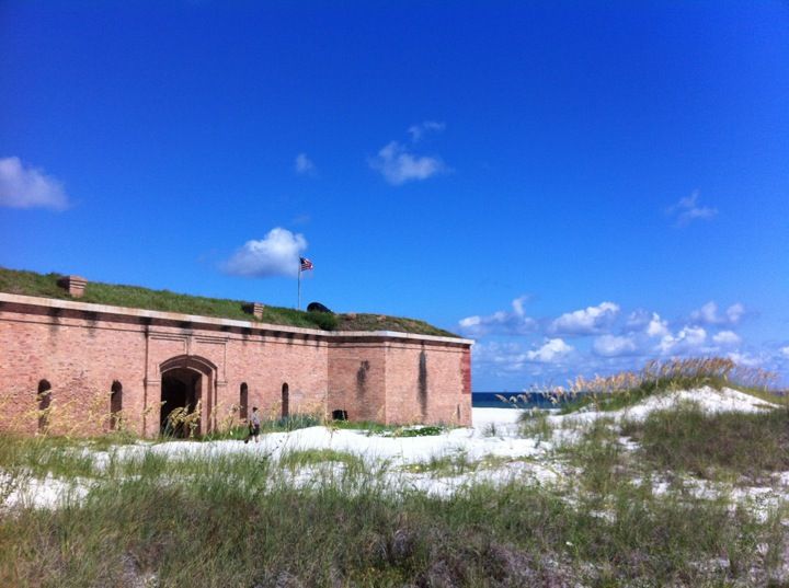 an old brick building with a green roof and grass growing on the top of it