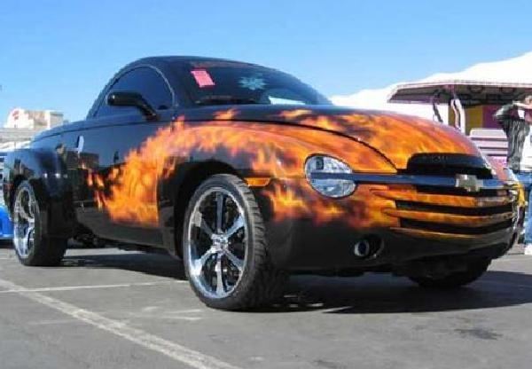 an orange and black car with flames painted on it's hood in a parking lot