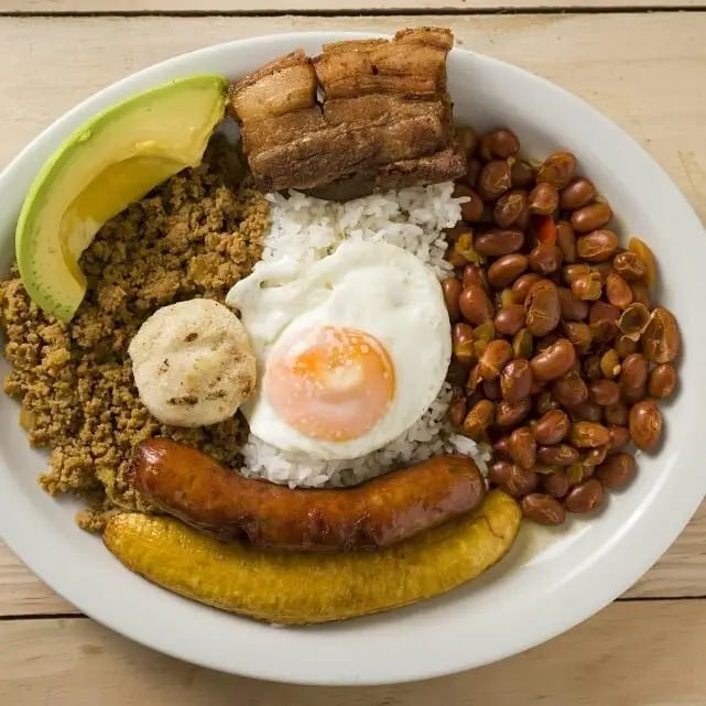 a white plate topped with meat, beans and an egg