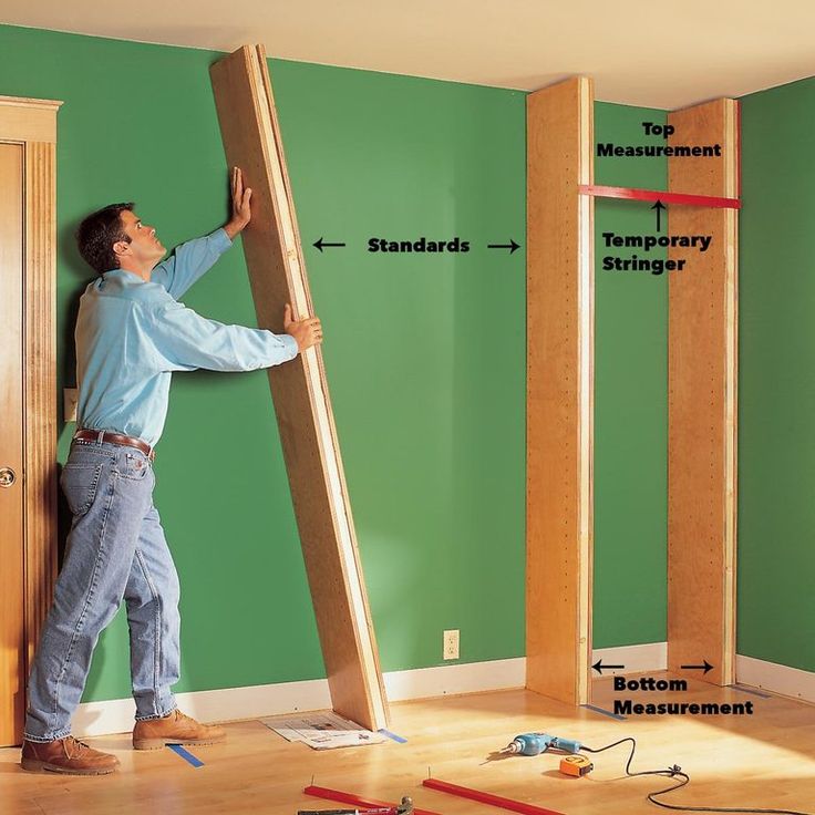 a man standing on top of a wooden floor next to a ladder and measuring tape