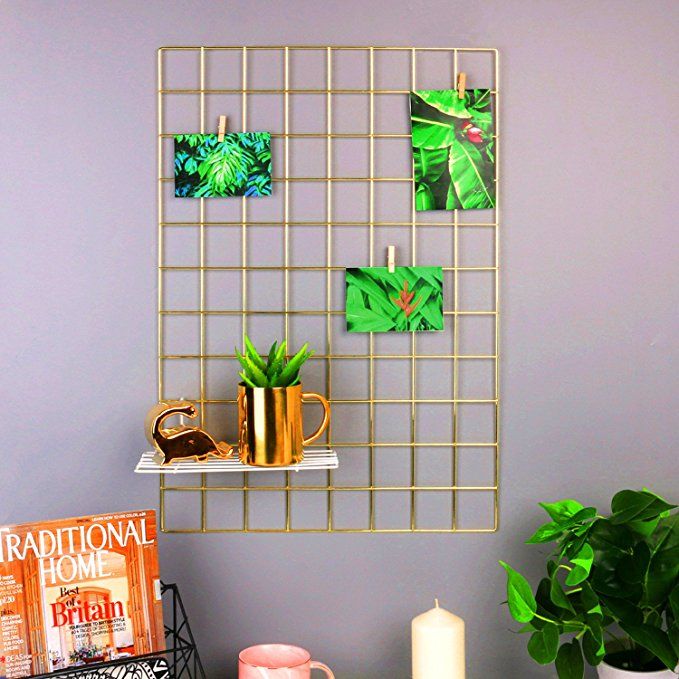 a shelf with some plants and pictures on it next to a candle, coffee cup, and magazines