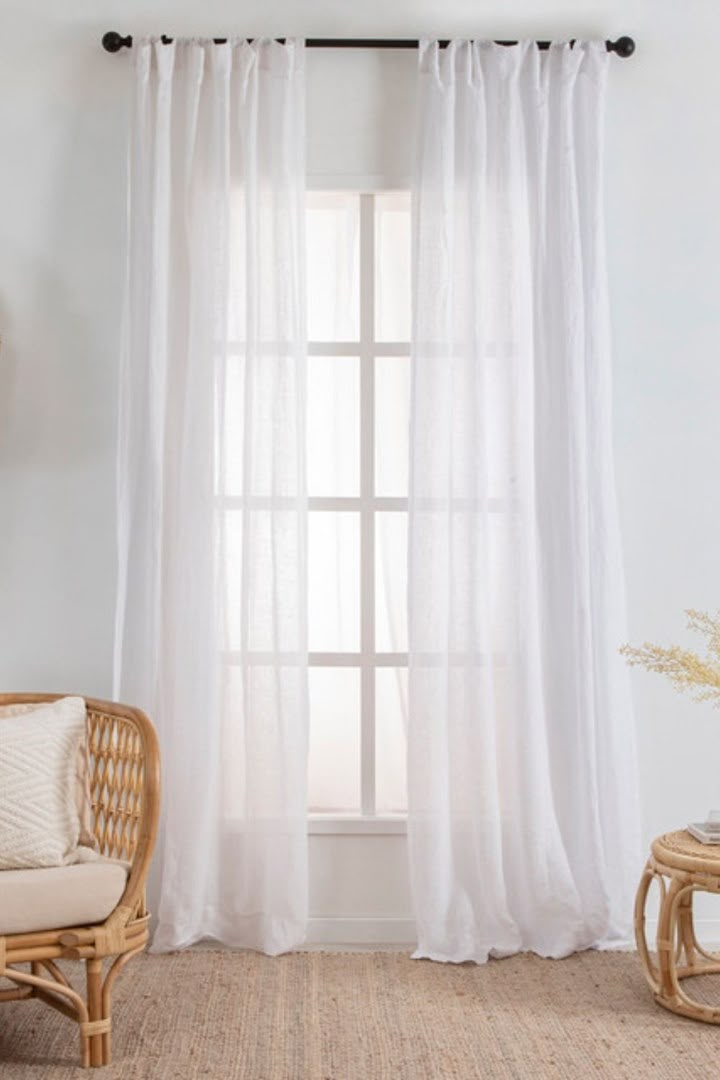 a living room with white curtains and wicker furniture