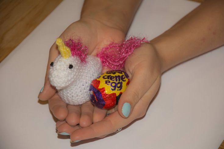 a person holding an easter egg with a unicorn on it and a candy bar in the other hand