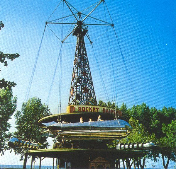 an amusement park with a ferris wheel in the middle and trees around it's edge