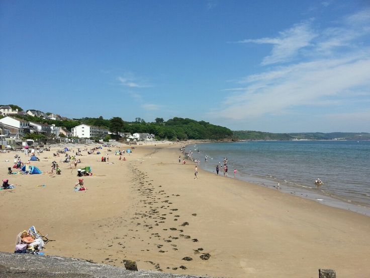 many people are on the beach and some have footprints in the sand near the water