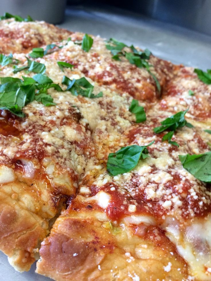 a close up of a pizza with cheese and basil on it's toppings