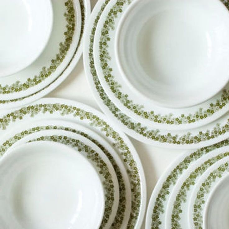 four white plates with green designs are stacked on top of each other in the same pattern