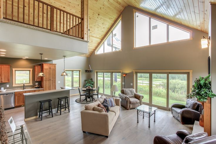 a living room filled with furniture next to an open kitchen and dining area in a house