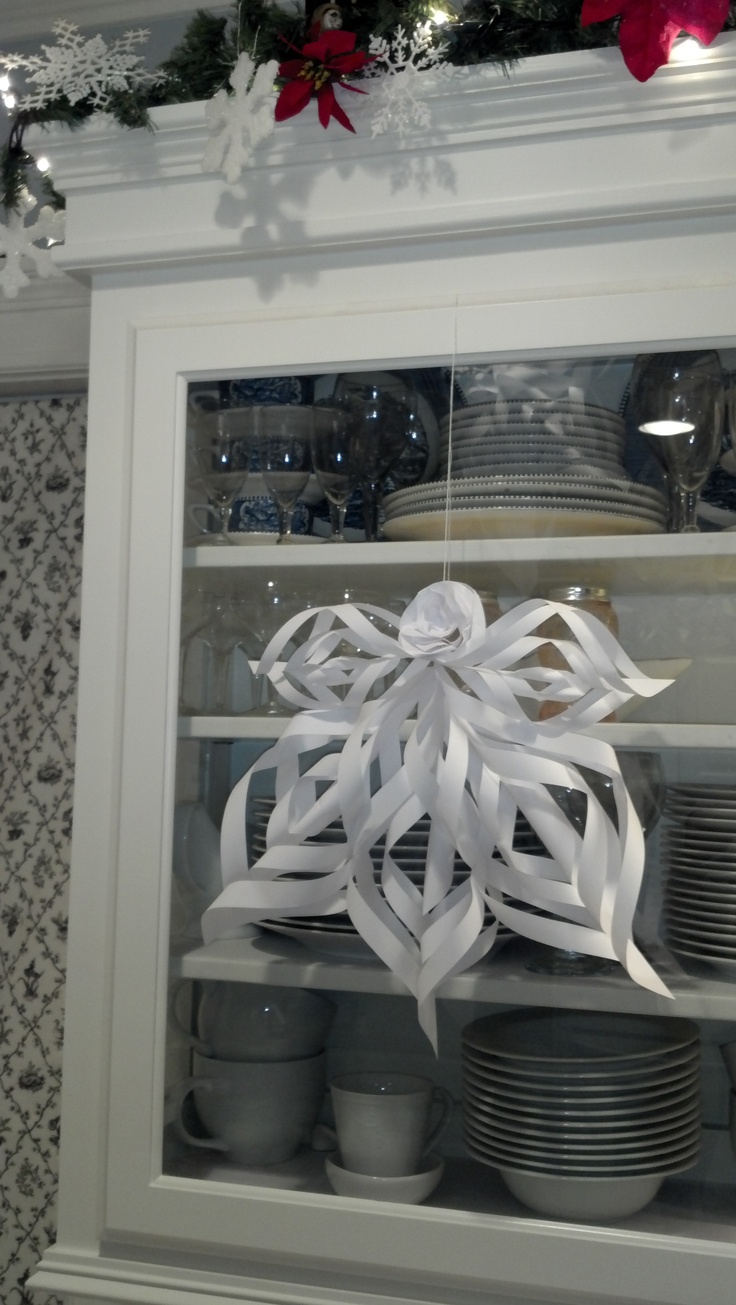 a display case filled with dishes and plates covered in white paper snowflakes