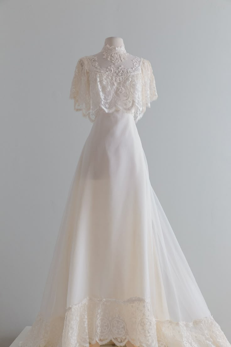 a white wedding dress on display against a gray background