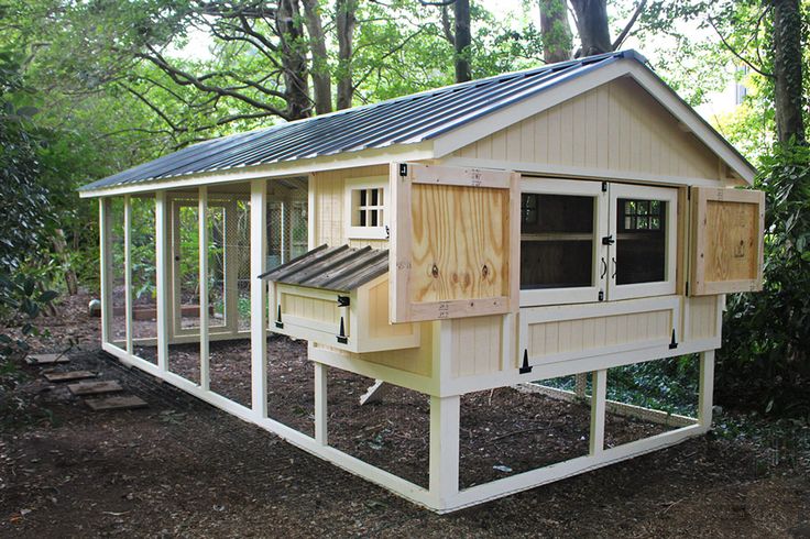 a chicken coop built into the side of a wooded area with trees in the background