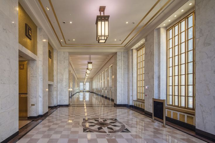 an empty hallway with marble floors and windows