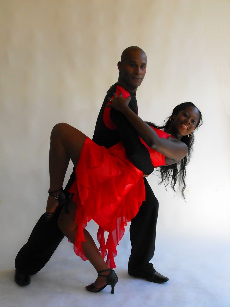 a man and woman are dancing together in red dress clothes with high heels on the dance floor