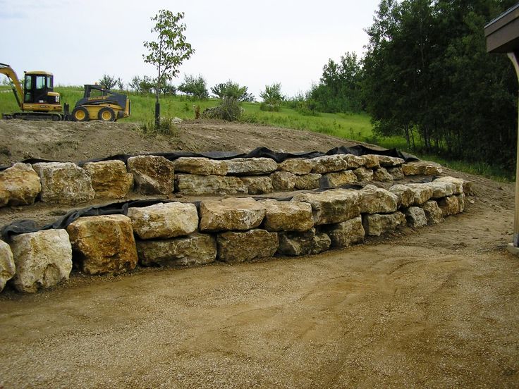 a large pile of rocks sitting on top of a dirt field next to a tractor