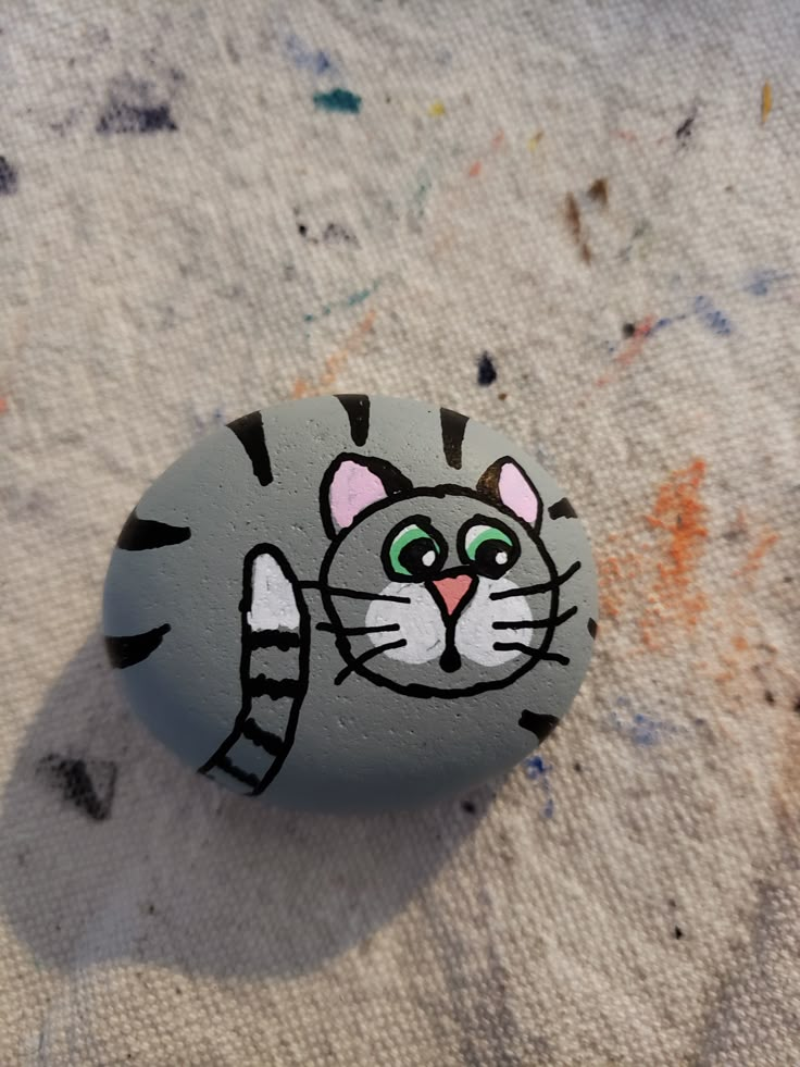 a painted rock with a cat's face on it