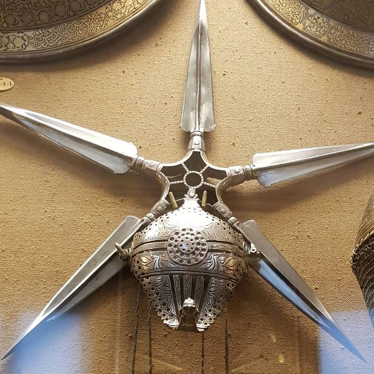 an intricately designed metal object on the side of a building with two large swords sticking out of it's center