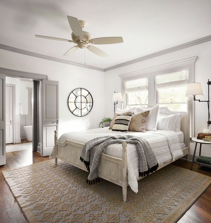 a bedroom with a bed, rug and ceiling fan in the middle of the room