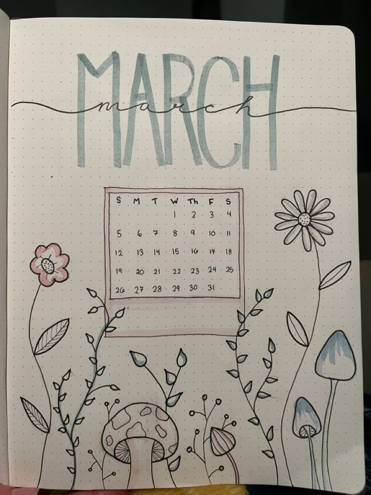 a hand holding a notebook with the word march written on it and flowers around it