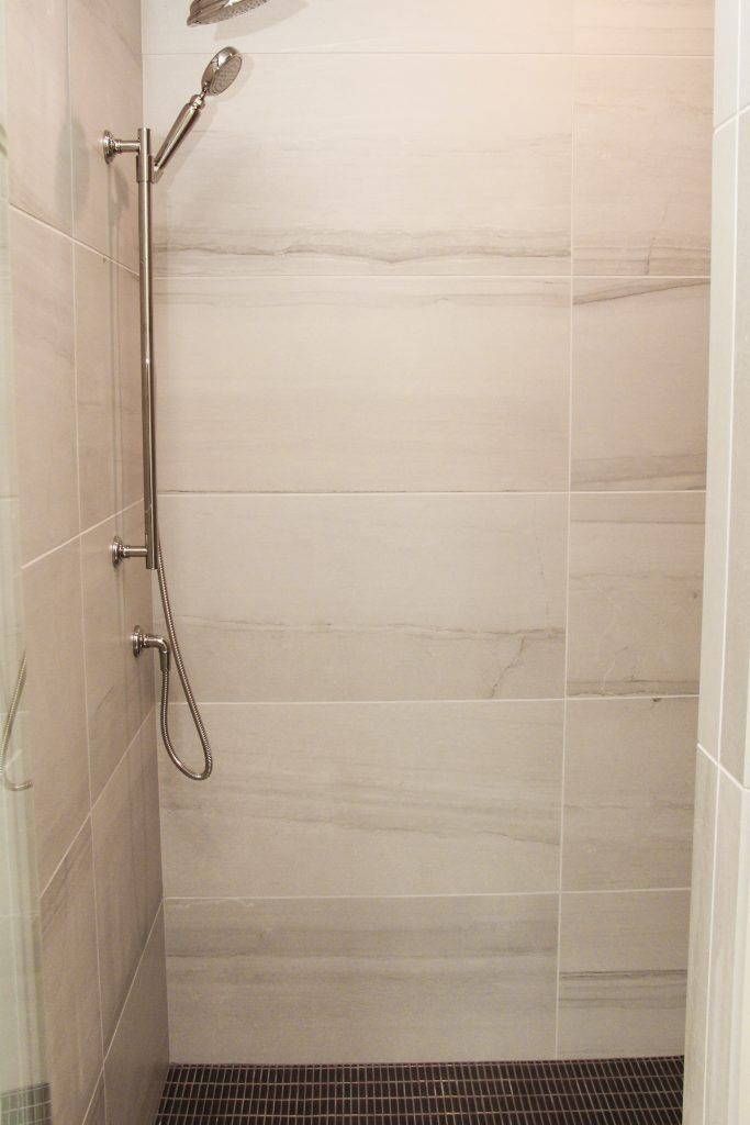 the shower head is mounted on the wall above the toilet and next to it is a tiled floor