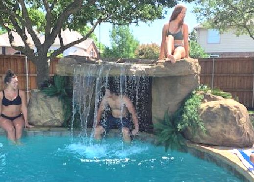 two women sitting on the edge of a swimming pool next to a man in a bathing suit