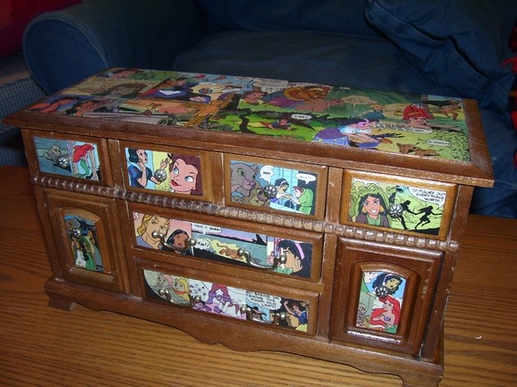 a wooden box with cartoon pictures on it sitting on a table next to a couch