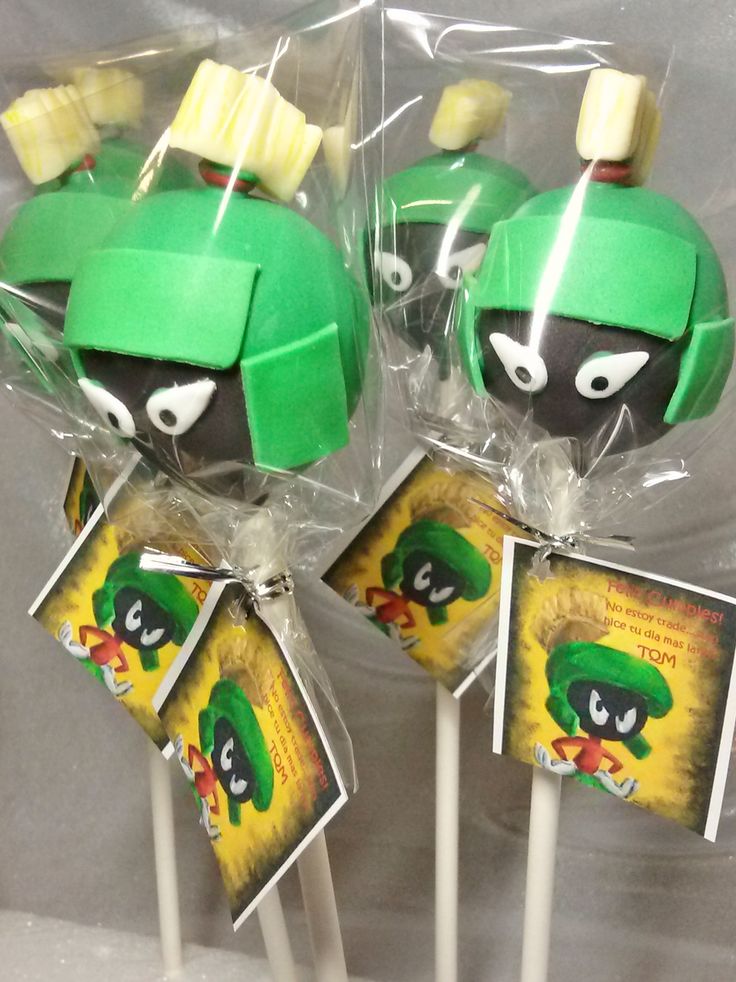 two lollipops are wrapped in plastic and have green hats on them,