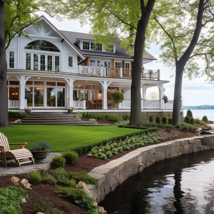 a large white house sitting on top of a lush green field next to a lake