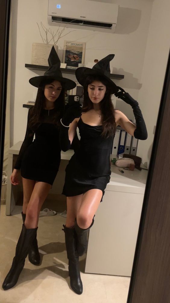 two women dressed up in witches costumes posing for the camera, both wearing black boots