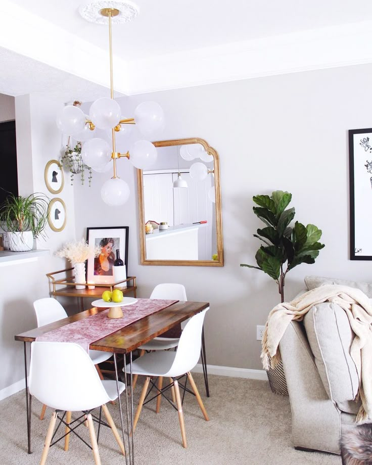 a dining room table and chairs in front of a couch with pictures on the wall