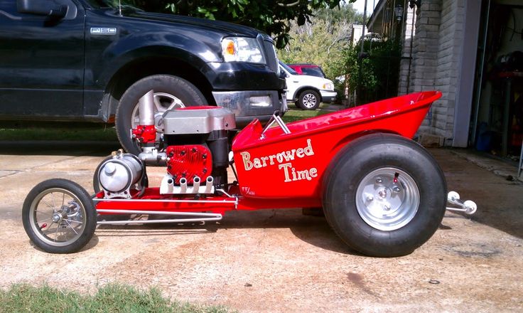 a red car is parked in front of a house with an engine on it's side