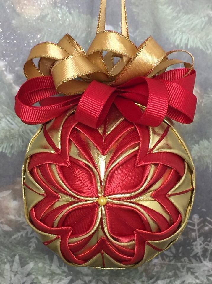 a red and gold ornament hanging from a christmas tree with ribbon on it