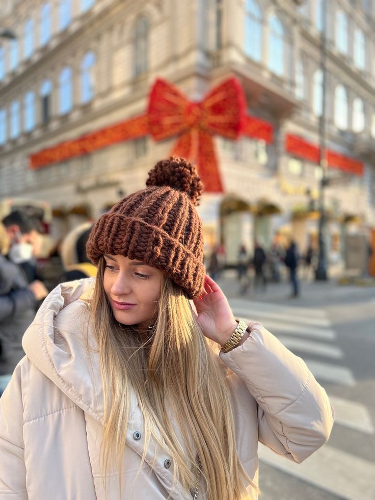 a woman wearing a brown hat while standing in front of a building with a red bow on it