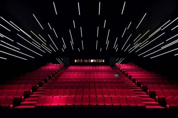 an empty auditorium filled with red seats and stars in the sky above it, all lit up at night