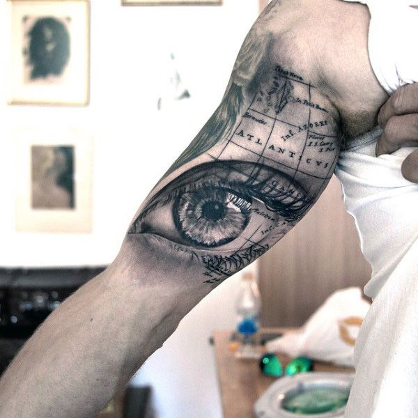 a man's arm with an eye and map tattoo on the left side of his arm