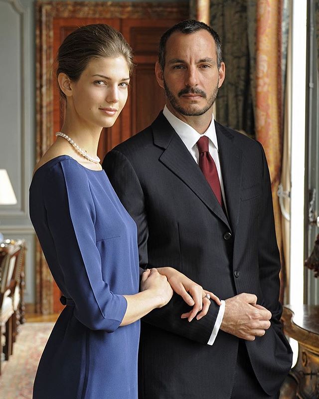 a man and woman standing next to each other in front of a table with chairs