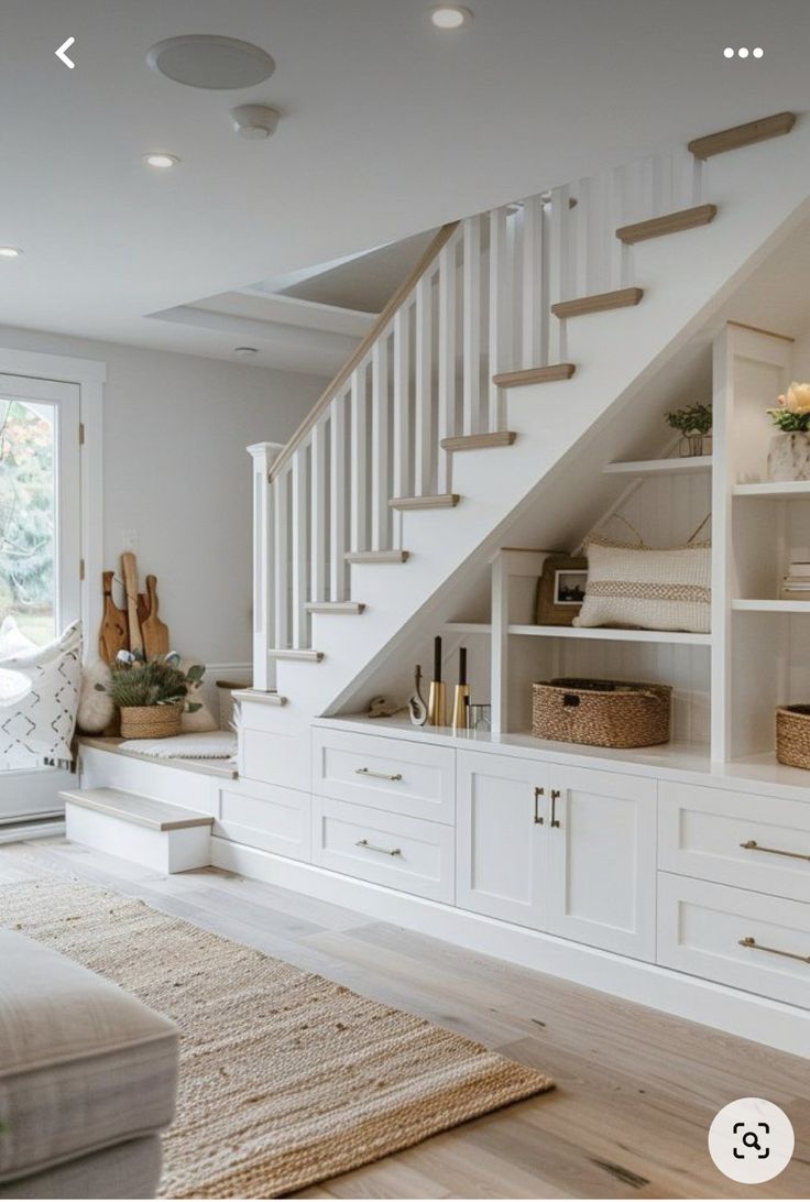 a living room filled with white furniture and lots of storage under the stair treads