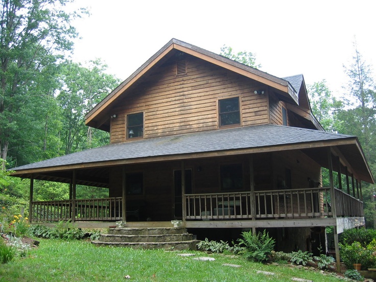 a large wooden house sitting on top of a lush green hillside