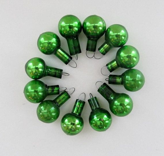 green christmas ornaments arranged in a circle on a white surface with one light turned off