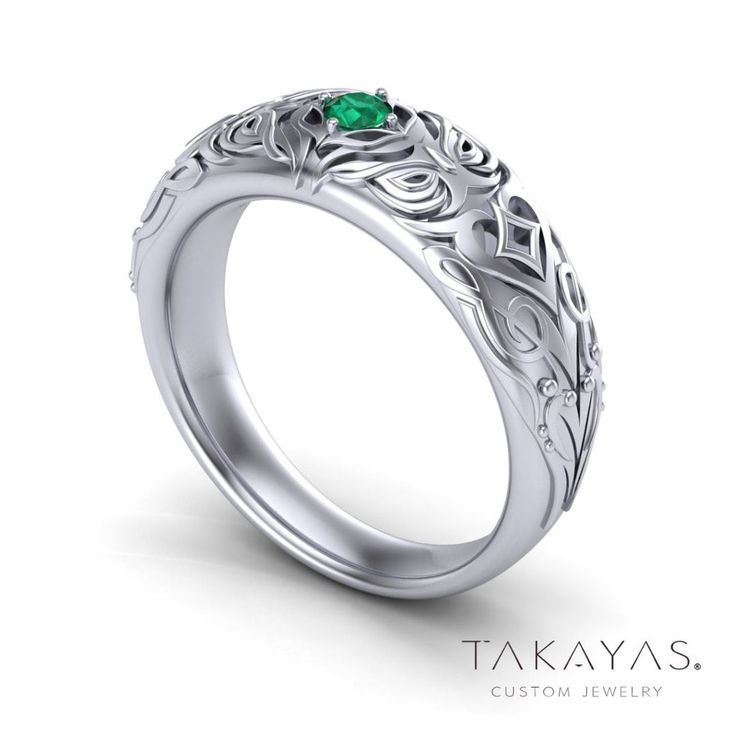 a white gold ring with an emerald stone in the center and filigrees on it