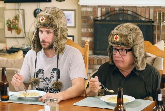 two men sitting at a table with plates of food