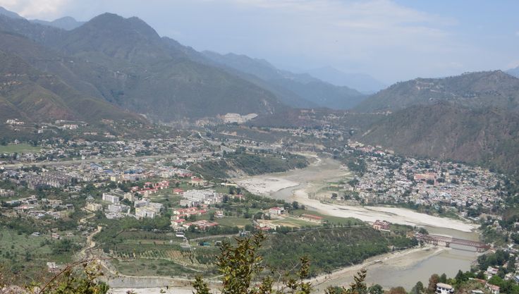 an aerial view of a small town in the middle of a valley with mountains behind it