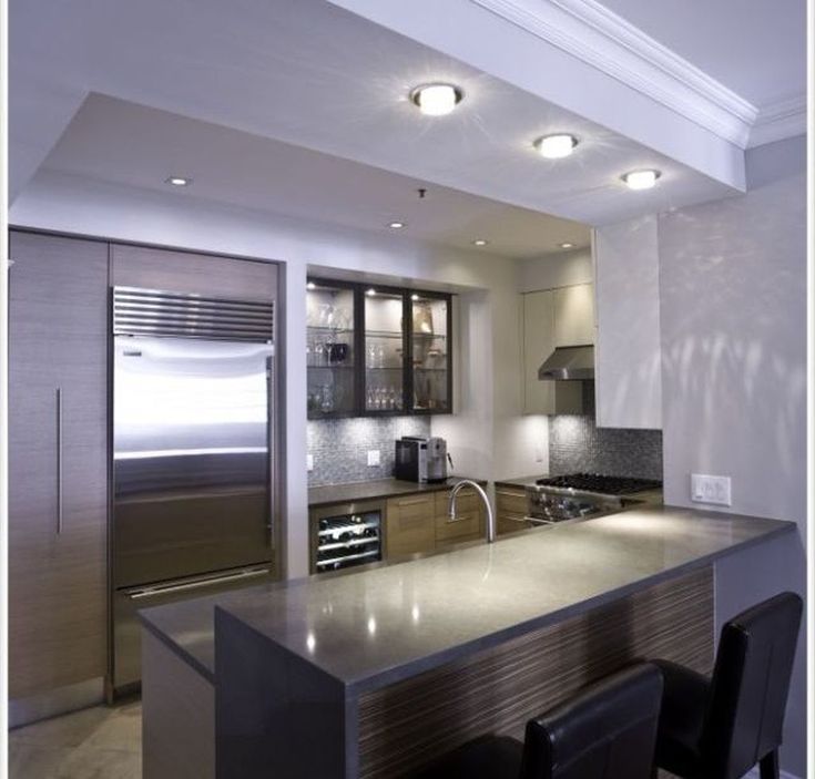 a modern kitchen with stainless steel appliances and counter tops, along with bar stools